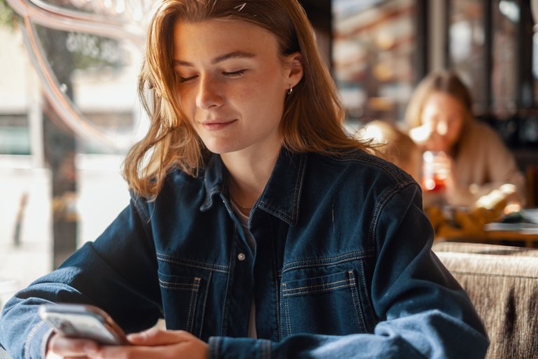 Bilde av en jente som sitter og ser på mobilen sin